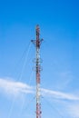 Tall red and white antenna on blue sky