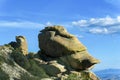 Tall rock formation on the edge of cliff or overhang on the top of mountain in afternoon sun with blue cloudy sky Royalty Free Stock Photo