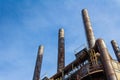 Tall, rusting smoke stacks silhouetted against a bright blue sky, abandoned industrial complex, copy space Royalty Free Stock Photo