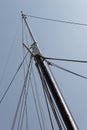 Tall ship mast with rope rigging lines, block and tackle, against a blue sky Royalty Free Stock Photo