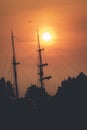 Tall ship rigging and flying bird silhouetted against fiery sunset Royalty Free Stock Photo