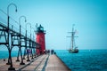 Tall ship sailing past a light house on a summer day