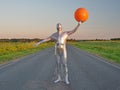 Tall slender man in silver suit is fully dressed in tight silver suit, stands in summer on an empty road, track and holds large