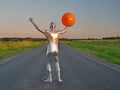 Tall slender man in silver suit is fully dressed in tight silver suit, stands in summer on an empty road, track and holds large