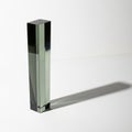 Tall Rectangular Prism Made of Dark Green Glass Casting a Long Shadow on a White Surface Royalty Free Stock Photo