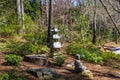 A tall slender stone Japanese lantern in the garden surrounded by brown fallen pine needles and lush green trees Royalty Free Stock Photo