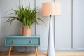 tall slimline bedside lamp with conical shade beside plant pot