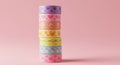 A tall stack of colorful decorative washi tapes with a subtle geometric pattern on a pink background Royalty Free Stock Photo