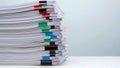 A tall stack of white paper documents, bound by colorful binder clips in red, black, green, and blue, against a plain light blue Royalty Free Stock Photo