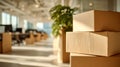 Moving boxes stacked in a bright modern office space with natural light and blurred background of desks and plants during Royalty Free Stock Photo