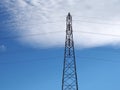 tall steel electricity pylon with cables against a blue sky with white clouds Royalty Free Stock Photo