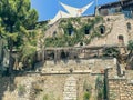 A tall stone building overgrown with grass, creeping grapes and moss. building with windows and roof, wooden balcony railings Royalty Free Stock Photo