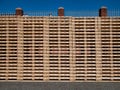 Tall, tidy stacks of clean, new, wooden pallets in sunshine with a blue sky