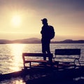 Tall tourist with backpack walk on beach at pedal boat in the sunset. Autumn at sea