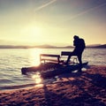 Tall tourist with backpack walk on beach at pedal boat in the sunset. Autumn at sea