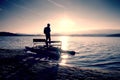 Tall tourist with backpack walk on beach at pedal boat in the sunset. Autumn at sea