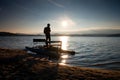 Tall tourist with backpack walk on beach at pedal boat in the sunset. Autumn at sea Royalty Free Stock Photo