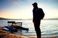 Tall tourist with backpack walk on beach at pedal boat in the sunset. Autumn at sea