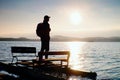 Tall tourist with backpack walk on beach at pedal boat in the sunset. Autumn at sea