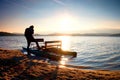 Tall tourist with backpack walk on beach at pedal boat in the sunset. Autumn at sea