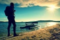 Tall tourist walk on beach at paddle boat in the sunset