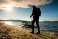 Tall tourist walk on beach at paddle boat in the sunset