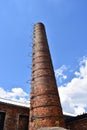 Tall vintage factory chimney made of red bricks with metal ledder