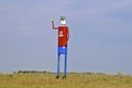 Tall welded steel man waves at traffic