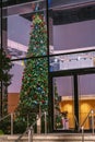 Tall and well decorated fir tree for Christmas or New Year celebrations in a hall of a huge office building. Rich company with