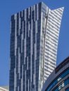 a tall white-blue building against a blue sky