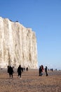 White chalk cliff face with pebble beach and lots of people walk