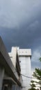 A tall, white modern building stands against a dramatically dark, overcast, and cloudy sky. Royalty Free Stock Photo