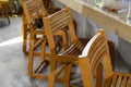 Tall wooden bar stools with backs stand in a row near the bar counter. Natural wood yellow. Close-up. Selective focus. Copy space Royalty Free Stock Photo