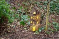 Tall wooden fairy house with yellow windows and fairy door, made from tree stump in Irish woodland fairy garden. Royalty Free Stock Photo