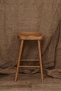 Tall Wooden Leg Stool on brown textile background Royalty Free Stock Photo