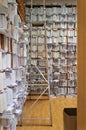 Tall wooden shelves with papers, all over the walls entirely, a document repository, a search ladder on the upper shelves