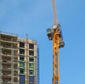 tall yellow crane working on a large multistory building under construction Royalty Free Stock Photo
