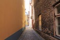 Narrow street of a medieval city. The wall is yellow on the left, and an old stone building on the right. Cobblestone road Royalty Free Stock Photo