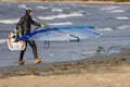 Tallinn, Estonia - October 18, 2008: A windsurfer in a suit carries a sailboard out of the sea