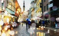 Tallinn old town street autumn rainy city blurred reflection light people walk under umbrellas on the street blue background cit