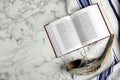 Tallit, shofar and open Torah on white marble table, flat lay with space for text. Rosh Hashanah celebration