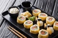 Tamagoyaki set sushi roll with rice, omelette, cheese, salmon and avocado served with sauces, wasabi and ginger on a plate.