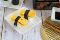 Tamagoyaki sushi or sweet egg on rice and seaweed wrap on square white plate. Delicious japanese food Royalty Free Stock Photo