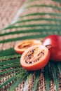 Tamarillo fruit or terong belanda with palm leaves on rattan background. Copy space. Tropical travel, exotic fruit. Vegan and