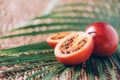 Tamarillo fruit or terong belanda with palm leaves on rattan background. Copy space. Tropical travel, exotic fruit. Vegan and