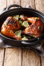 Tamarind chicken quarter leg with lime close-up in a frying pan. vertical