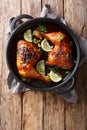 Tamarind chicken quarter leg with lime close-up in a frying pan. Vertical top view