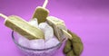 Tamarind-flavored brown ice lollipop inside a deep plate with ice on a light purple background, with tamarind pods on the sides