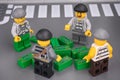 Four Lego robber minifigures looking at pile of cash
