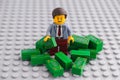 Lego businessman minifigure standing in a pile of cash